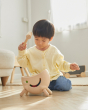 Young child sat on a wooden floor playing with the PlanToys miracle pounding toy