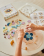 Close up of some hands arranging the PlanToys wooden mandala toy blocks on a white table cloth