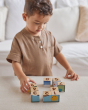 Young boy ordering the numbers on the back of the PlanToys plastic-free animal puzzle blocks on a beige sofa