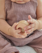 Close up of the PlanToys wooden sensory ball in a toddler's hand showing the fluffy texture inside