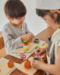 Close up of a young boy stacking food from the PlanToys wooden cheese and charcuterie play food set