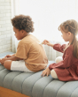 Girl drawing on a young boys back with the PlanToys wooden touch and guess game on a grey sofa