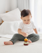 Young boy playing with the PlanToys Waldorf stacking rings toy on a white bed