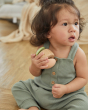 Close up of young girl sat down holding the PlanToys wooden clapping roller sensory toy