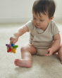 Close up of a toddler sat on the floor holding the PlanToys wooden flexi jellyfish baby toy