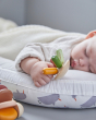 Close up of a sleeping baby holding onto the PlanToys plastic-free wooden flexi jellyfish toy