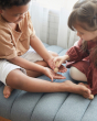 Close up of children playing with the PlanToys wooden touch and guess sensory game on a grey sofa