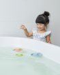Girl leaning over a bath tub playing with some PlanToys natural rubber boat toys, floating in the water 