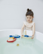 Girl playing in a bath with the Plan Toys eco-friendly sail boat, cargo ship and tugboat toys