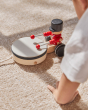 Close up of the PlanToys kids pull along drummer toy on a beige carpet next to a childs hand