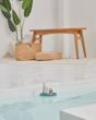 PlanToys plastic-free sailing boat bath toy in some water in front of a wooden bench