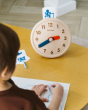 Close up of child drawing on some paper next to the PlanToys wooden activities clock