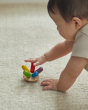 Close up of young child spinning the PlanToys flexi jellyfish toy around on a beige carpet