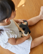 Close up of girl sat on a wooden floor holding the PlanToys plastic-free wooden climbing gorilla toy