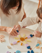 Close up of mother and daughter playing with the PlanToys wooden Mandala set on a white table