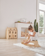 Young girl sat on the PlanToys children's palomino rocking horse on a white fluffy rug in a light playroom