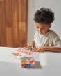 Close up of boy looking at different patterns to make with the PlanToys stacking geo pattern blocks on a white table