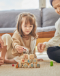 Close up of girl and woman on the floor, stacking the PlanToys wooden storytelling dice