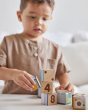 Close up of boy stacking the Waldorf PlanToys animal puzzle toy blocks on a beige cushion