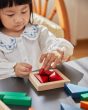 Close up of young girl sat playing with the PlanToys plastic-free wooden fraction blocks set
