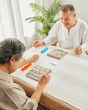 2 people sat at a table playing with the PlanToys wooden bingo board game