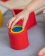 Close up of a child's hand reaching out to grab the PlanToys wooden nesting shapes set