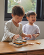 Two boys playing with the PlanToys plastic-free wooden orchard shape sorting toy on a wooden table