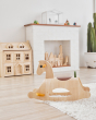PlanToys childrens wooden Palomino rocking horse on a white fluffy rug in front of a fireplace and Victorian dollhouse