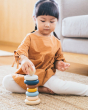 Girl sat on the floor playing with the PlanToys coloured wooden stacking rings