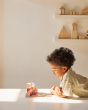Young boy leaning over to look closely at the PlanToys coloured wooden stacking toy blocks on a white table