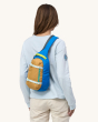 An adult wearing the Patagonia Atom Sling 8L - Patchwork bag in Vessel Blue on their shoulder