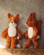 Senger Animal Baby Squirrel and Fox Toy. Made entirely of sustainably-produced cotton plush, and can safely be sucked or chewed, a soft body plush toy squirrel and fox in light brown/ginger with a white fluffy belly, on a textured grey background and wood