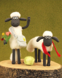 Shaun the Sheep on Two legs and Four legs stood next to each other on a wooden log base.