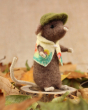 Gardening mouse is busy in the garden, wondering what to plant next. Stood on a circular wooden log and surrounded by green and brown tree leaves