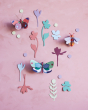 Studio Roof card butterfly wall hangings on a pink wall surrounded by card leaves