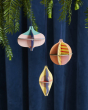 Studio Roof plastic-free hanging Christmas baubles hanging from a Christmas tree in front of a dark blue curtain