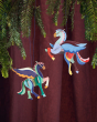 Studio Roof card craft Pegasus hanging decorations hanging from a Christmas tree in front of a deep red curtain