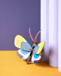 Studio roof colourful yellow monarch butterfly cardboard wall decoration leaning against some light purple tubes on an orange floor