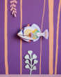 Studio Roof Picasso fish plastic-free wall decoration on a purple wall next to some card plants