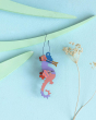 Close up of Studio Roof renewable plastic-free seahorse decoration hanging from some turquoise wood in front of a blue wall