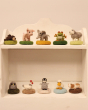 Ten of The Makerss - Amiguwoolli Tiny Mini Needle Felt Figures sat on white shelves. On the top is the snoozing bear, pig, elephant, frog and sheep. On the bottom shelf is the tiny owl, chicken, tiny penguin, duck and guinea pig felt figures.