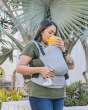 Close up of a woman kissing a young baby in the Tula eco-friendly soft free to grow baby carrier in front of a large palm tree