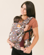 Woman stood carrying a baby on her front in the Tula soft structured fox tail baby carrier