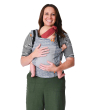 Woman stood on a white background carrying a baby in the Tula free to grow coast beyond baby carrier