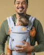 Man carrying a baby in the Tula explore linen baby carrier on a beige background
