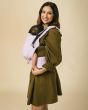 Woman stood on a beige background holding a baby in a Tula organic cotton FTG baby carrier