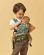 Young boy looking down at a cuddly toy sat in his Tula dinosaur print toy carrier on his front