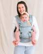 Woman stood in front of a white background with a toddler in a Tula blue harbor skies adjustable baby carrier