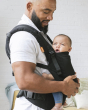 Woman stood holding a baby in a Tula FTG urbanista baby carrier