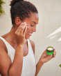 A close up photo of a person using the Weleda nourishing day cream on their skin